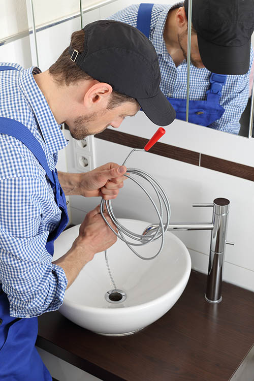 Plumber cleaning a pipe drain with a Spiral