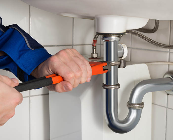 Male Plumber Repairing Sink In Bathroom